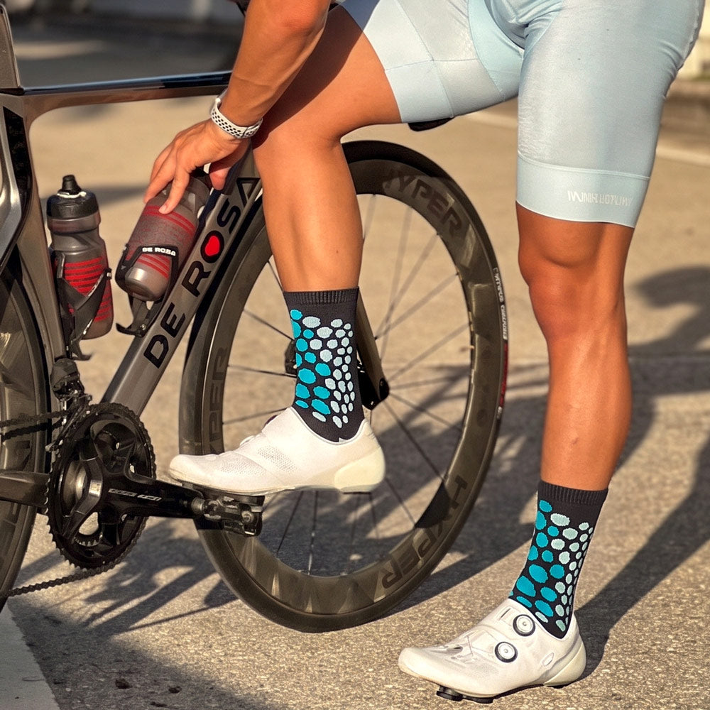 Teal and black cheetah print socks worn by male cyclist next to his bike