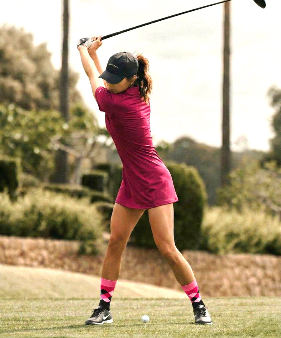 Rhino Print Pink & Black Argyle Crew Socks shown worn by female golfer in a pink dress at the golf course