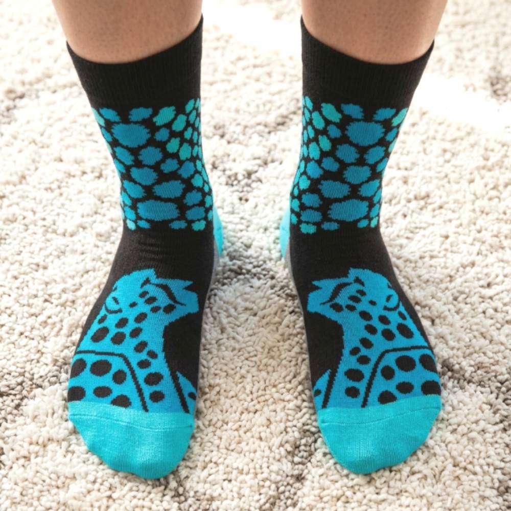 Black socks with teal cheetah pattern on a beige carpet