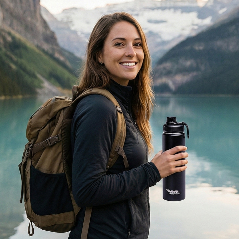 Woman with a backpack and Shongolulu water bottle in front of a mountain lake