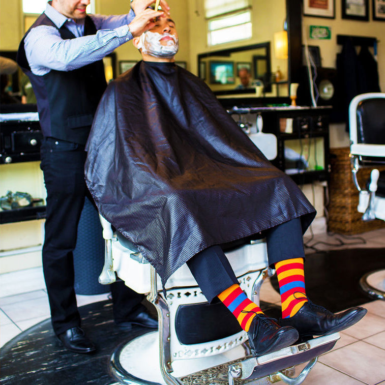 man wearing colorful striped socks while getting a haircut