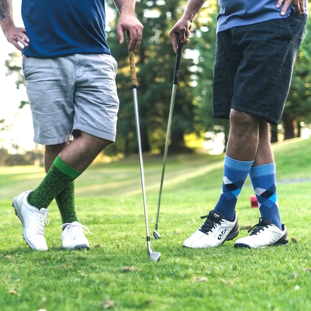 Two golfers on a golf course with one wearing Shongolulu green lion print socks and the other blue argyle elephant print socks.